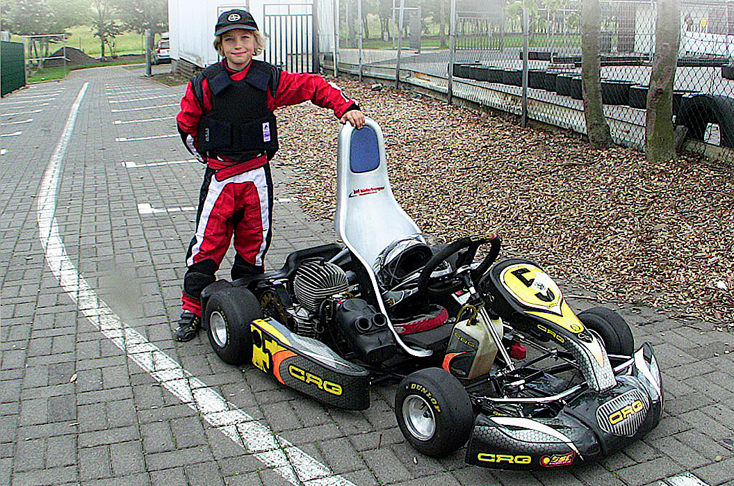 7-jähriger Kartfahrer Denis Robin Wolf im Rennanzug, stolz neben seinem CRG Rennkart stehend