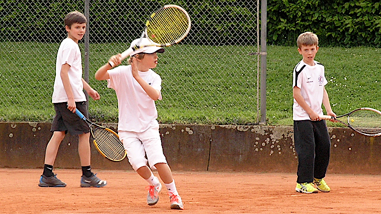 8-jähriger Tennisspieler Denis Robin Wolf, in Vorbereitung zu einem Vorhandschlag, mit zwei zuschauenden Kindern